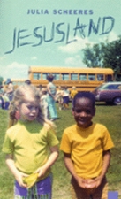 A white little girl standing with a black little boy in front of a school bus.