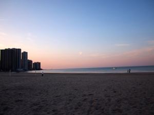 Image of a sunset over a lake. Buildings are right on the water's edge.