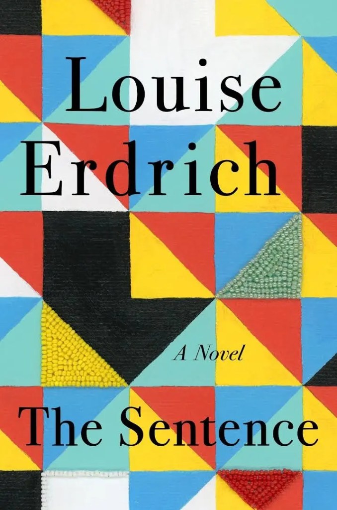 Image of a digital book cover. A quilt in white, yellow, black, red, and turquoise is behind the title.